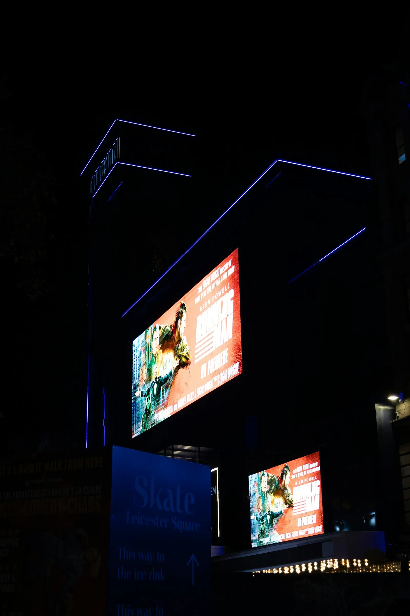 Fachada de edifício com telas de LED acesas à noite.
